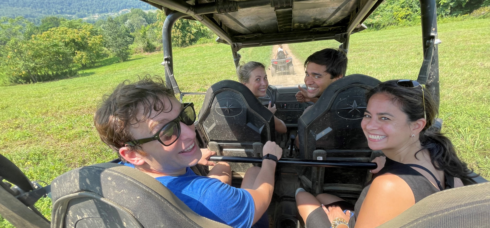 Four Viking employees in an open-air vehicle over a lush field of grass