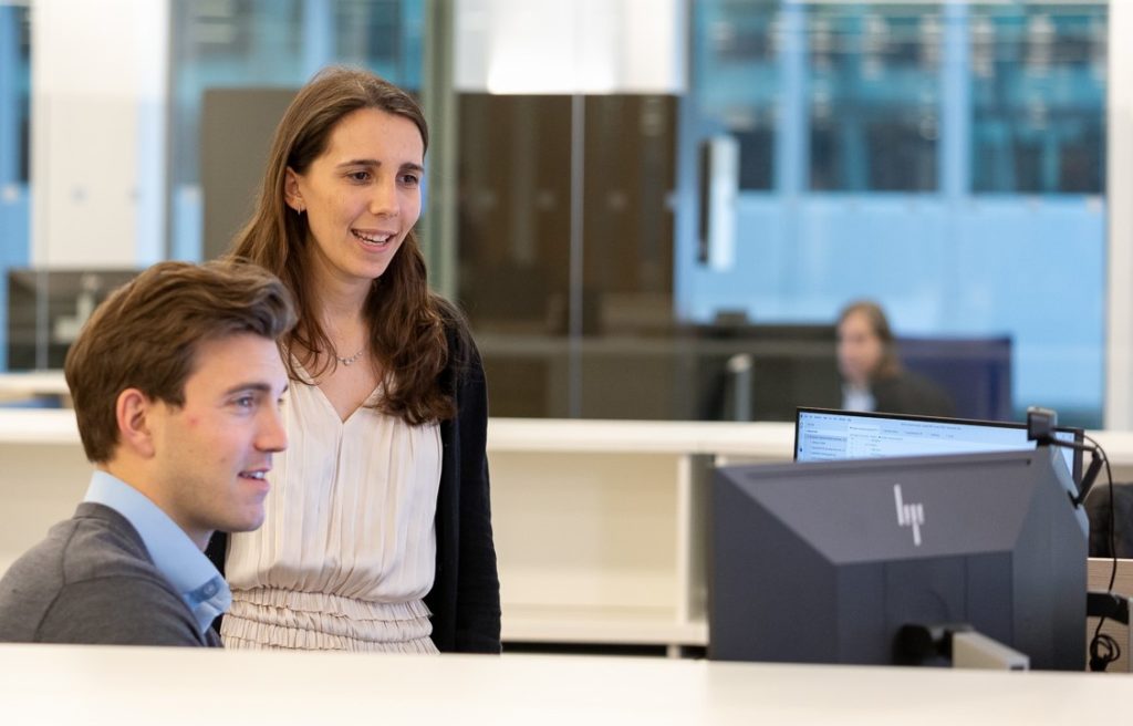 030922_Viking-NY_Candid-Office_1844_Lo-Res_cropped Two colleagues gather at a monitor and have a discussion.